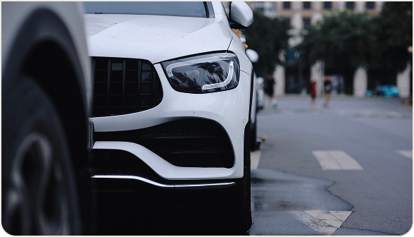 Front of a white SUV parked on a wet city street